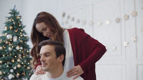 Closeup-pretty-wife-massaging-husband-shoulders-in-luxury-house.