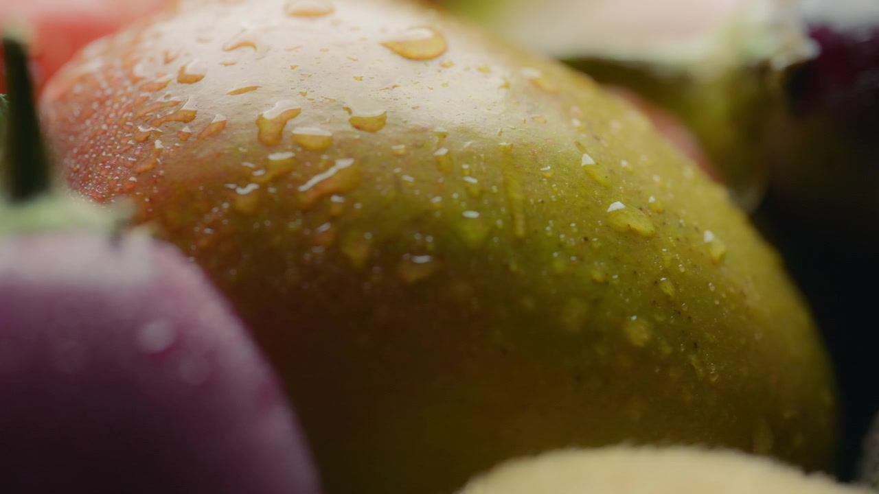 Mango fresco ricoperto di goccioline d'acqua tra un assortimento di frutta e verdura.