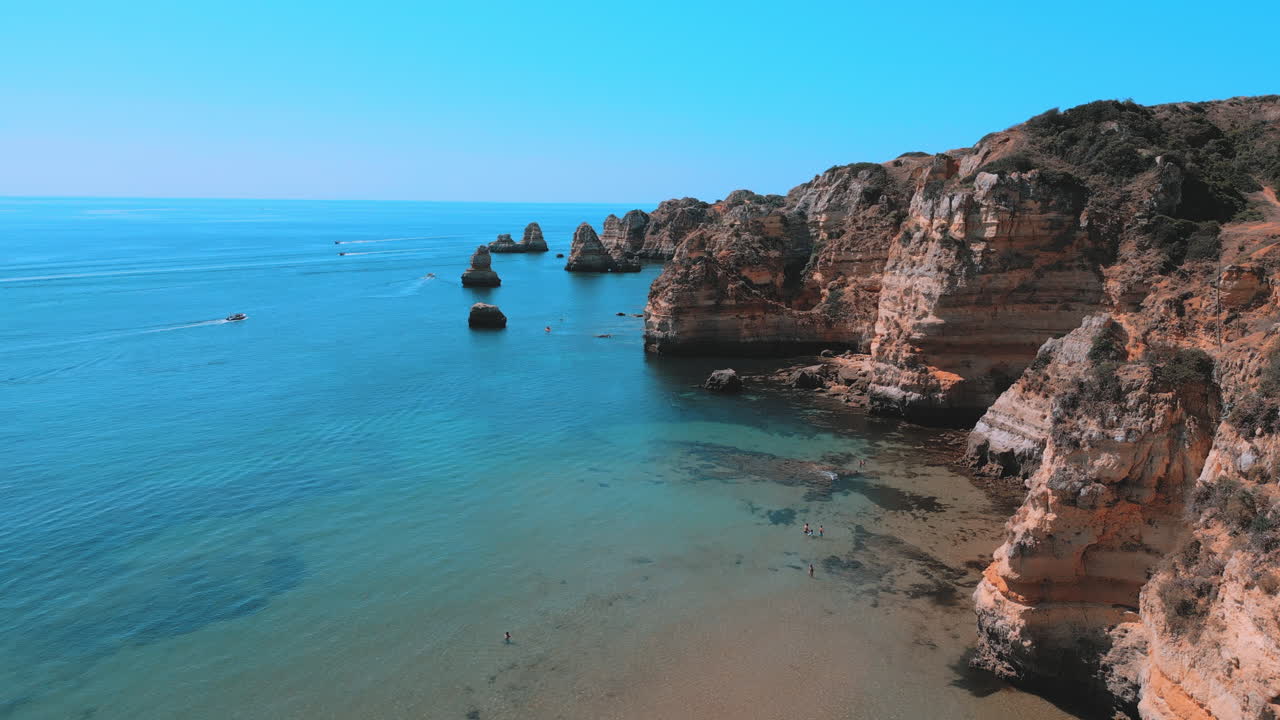 Rocky cliffs and beautiful blue ocean during the summer in Praia Dona Ana in the Algarve in Portugal, aerial drone view