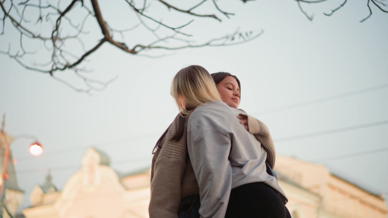 Due giovani donne che si incontrano e si abbracciano all'aperto.