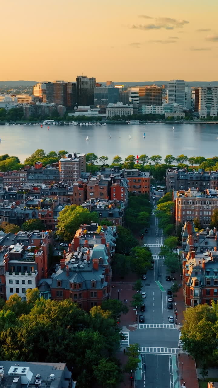 View on the Charles River in Boston flying above the city streets. Residential area built with blocks of flats at the waterfront of the river. Vertical video