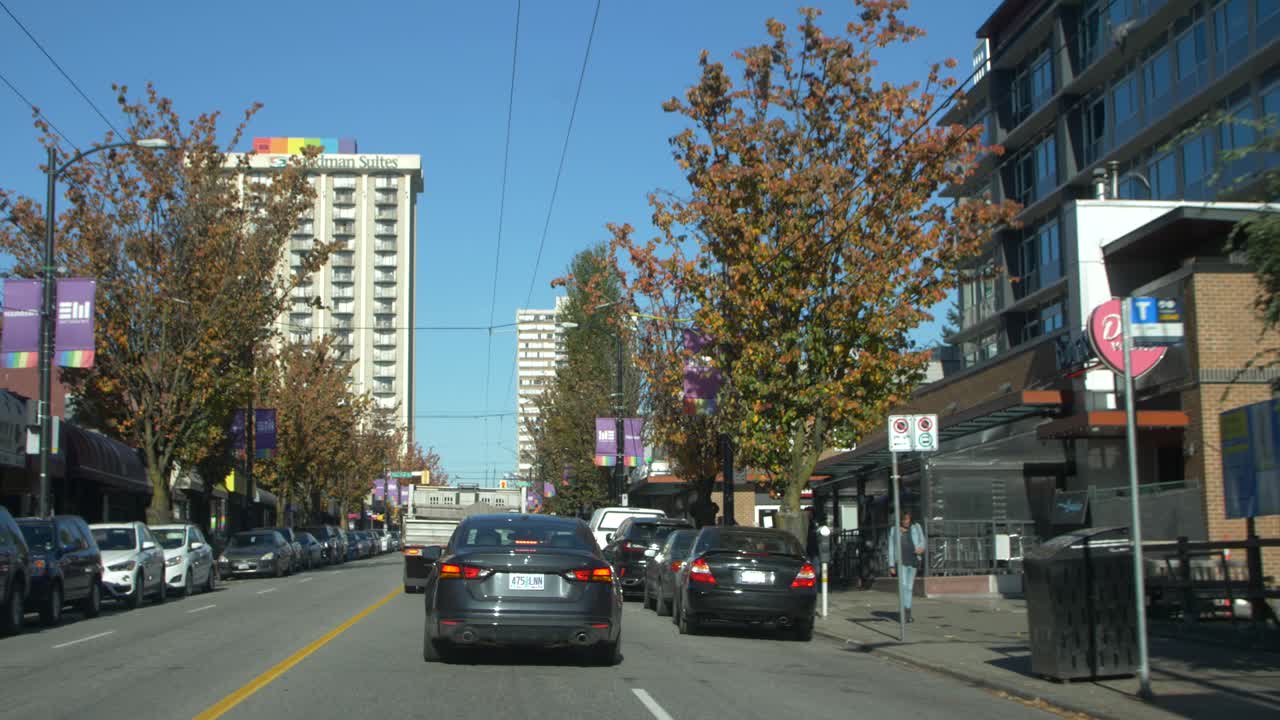 Driving through a vibrant city street with autumn trees and buildings