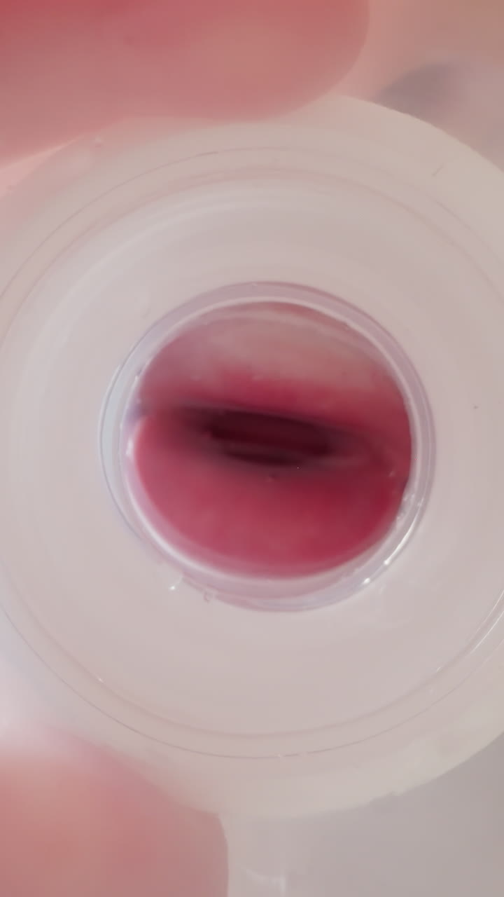 Child holds plastic bottle. Kid mouth clamps and unclasps nipple blowing out bubbles into water. Thirsty boy drinks liquid at home macro low angle shot