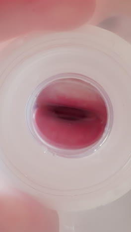 child holds plastic bottle. kid mouth clamps and unclasps nipple blowing out bubbles into water. thirsty boy drinks liquid at home macro low angle shot