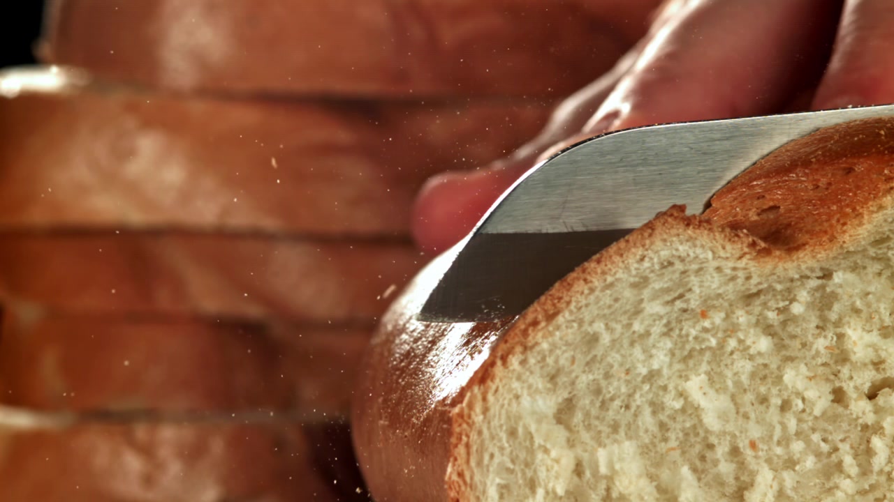 Close-up of a Serrated Knife Slicing Fresh Bread in Slow Motion