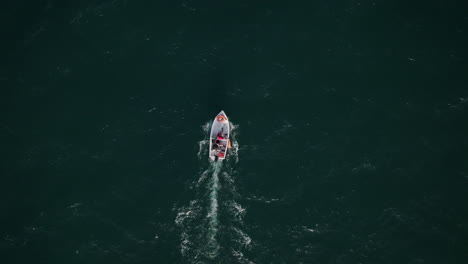 Imágenes-Aéreas-De-Arriba-Hacia-Abajo-Del-Mar-Con-Un-Pequeño-Bote-Moviéndose-Lentamente-A-Través-De-Las-Olas-Agitadas