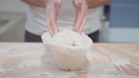 closeup of hands of a baker, making a bread loaf out of dough in a form