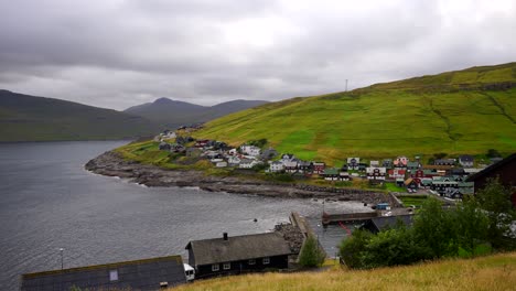 static wide shot showing kvivik village with colorful houses and tranquil atlantic ocean during cloudy day