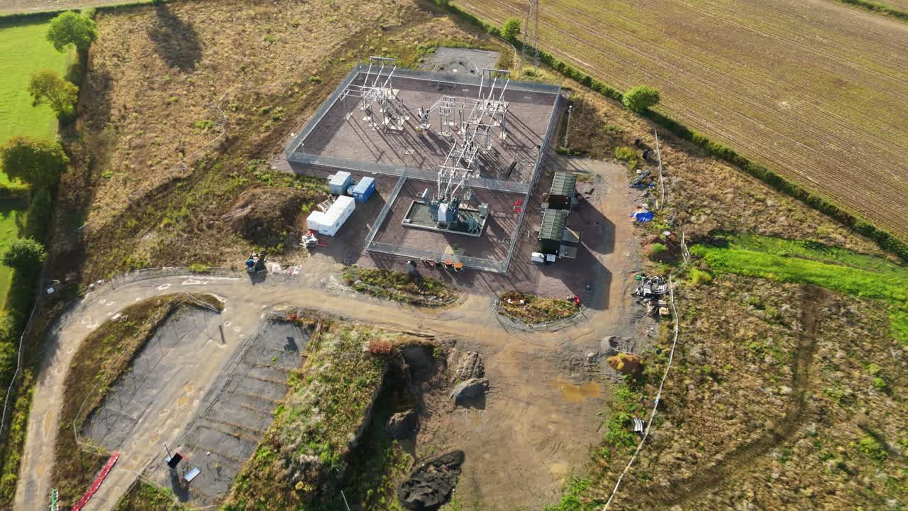 Drone footage of Coalville power plant substation showing transformers, pylons, and electrical grid infrastructure from above on a clear day