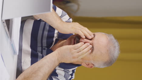 vertical video of home office worker old man has eye pain.