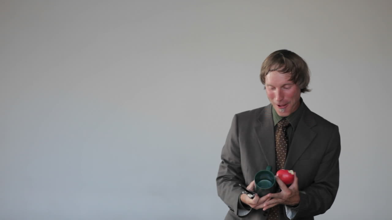 남자는 사과 컵과 전화에 응답하고 컵에 사과를 잡는 전화 저글링 행위를