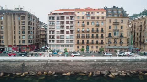 Aerial-trucking-pan-of-coastal-sea-wall-and-building-facades-of-San-Sebastian-in-Spain,-colonial-architecture