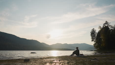 woman throws stones into water on picnic. lady silhouette with food basket enjoys peaceful picnic alone surrounded by beauty of nature in warm autumn evening