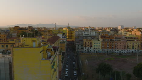 Volar-Por-Encima-De-La-Calle-En-La-Ciudad.-Casas-De-Apartamentos-De-Color-Iluminadas-Por-El-Sol-Naciente.-Varias-Casas-En-Casco-Urbano.-Roma,-Italia