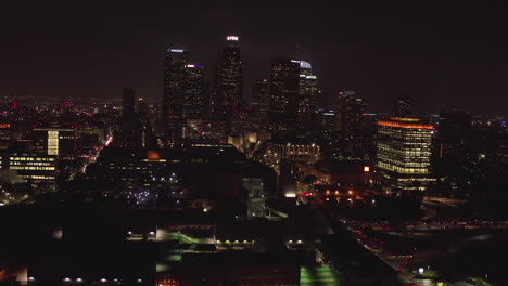 Aéreo:-Volando-Hacia-Los-Rascacielos-Del-Centro,-El-Horizonte-De-Los-ángeles,-California-De-Noche-Con-Luces-De-La-Ciudad,