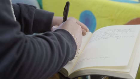 Mano-De-Mujer-Escribiendo-Un-Cuaderno,-Escribiendo-Notas,-Concepto-De-Estilo-De-Vida-Y-Trabajo-En-Casa