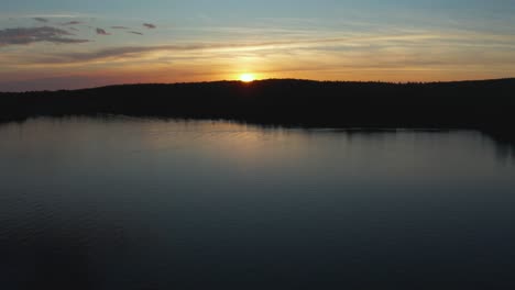 drone flying over a quiet lake going towards a colorful sunset, in the eastern township, quebec, canada