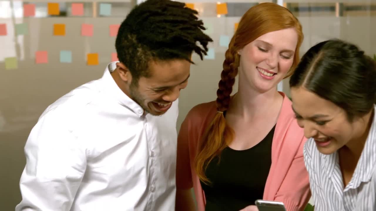 창의적인  ⁇ 스터 팀이 휴대폰에 있는 사진을 웃고 있습니다.