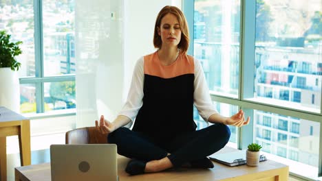 female executive meditating at her desk