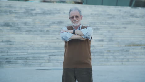 good looking old man standing outside, making hands crossed