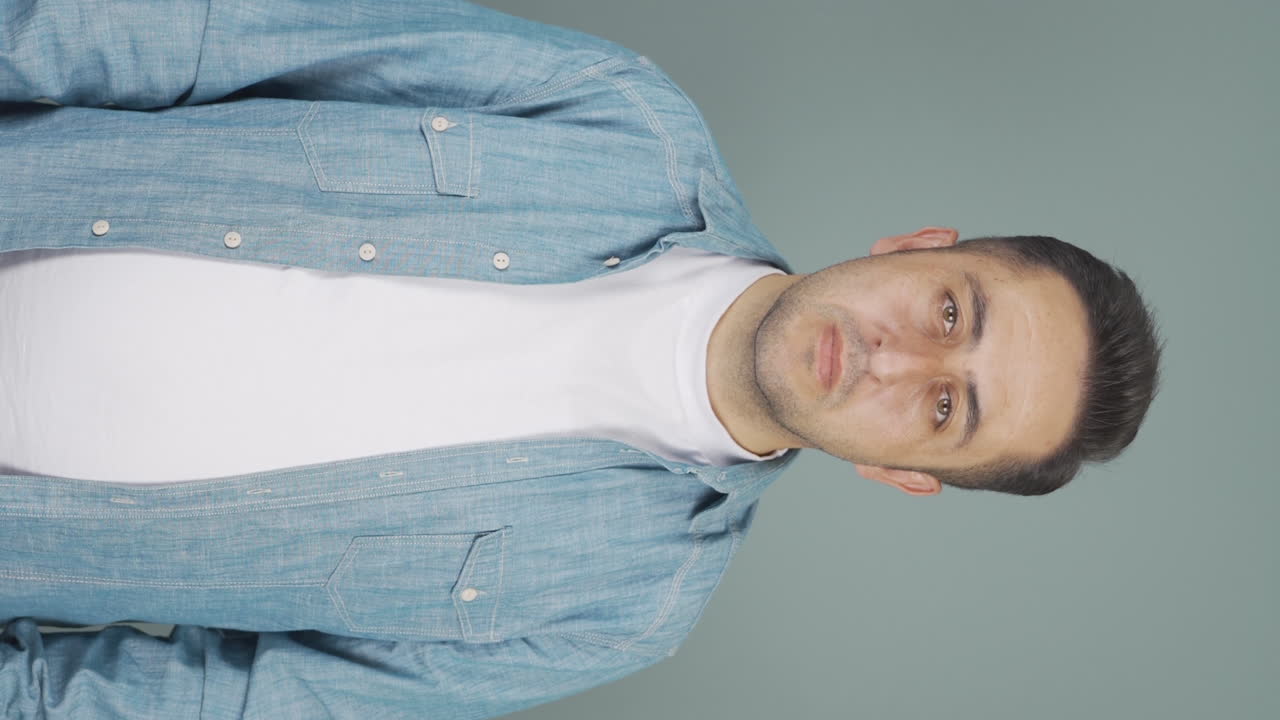 video vertical de un hombre mirando a la cámara con una expresión aburrida.