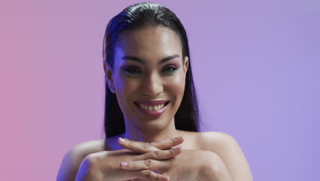 mujer biracial sonriente con cabello negro y maquillaje mirando a la cámara, copia espacio, cámara lenta