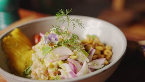 preparation of ceviche - slow motion skilful chef finalising the dish by garnishing with edible flower using a thong, cooking scene concept