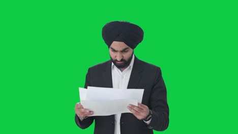 frustrated sikh indian businessman reading company reports green screen