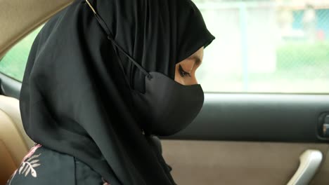 woman wearing hijab and mask in a car