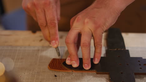 worker cuts leather belt edge with knife on workbench