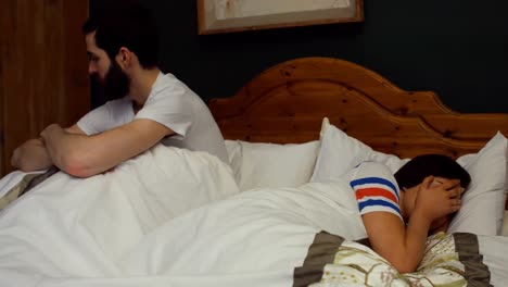 couple ignoring each other on bed in bedroom