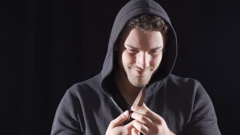 hombre psicópata vagabundo mirando a la cámara con un cuchillo en la mano.
