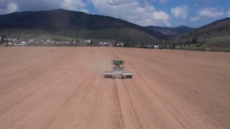 vista aérea del tractor con rodillos y arado moviéndose en tierra agrícola polvorienta