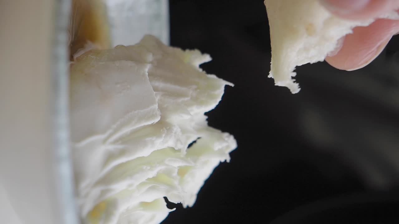 A hand holding a sandwich with cream