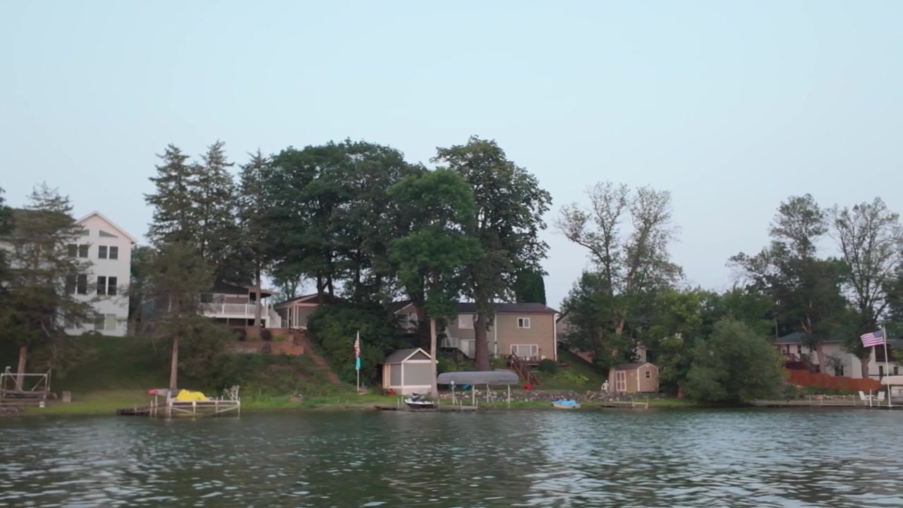 Ripresa con gimbal da una barca in movimento che passa accanto a delle baite sul lago Center durante l'estate in Minnesota. 4K