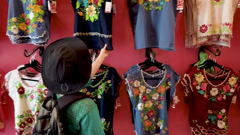 woman tourist looks at fashionable designer huipil blouses in merida, mexico