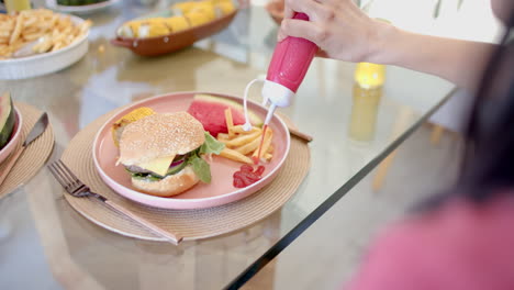squeezing ketchup on fries, person enjoying burger and fries with diverse friends