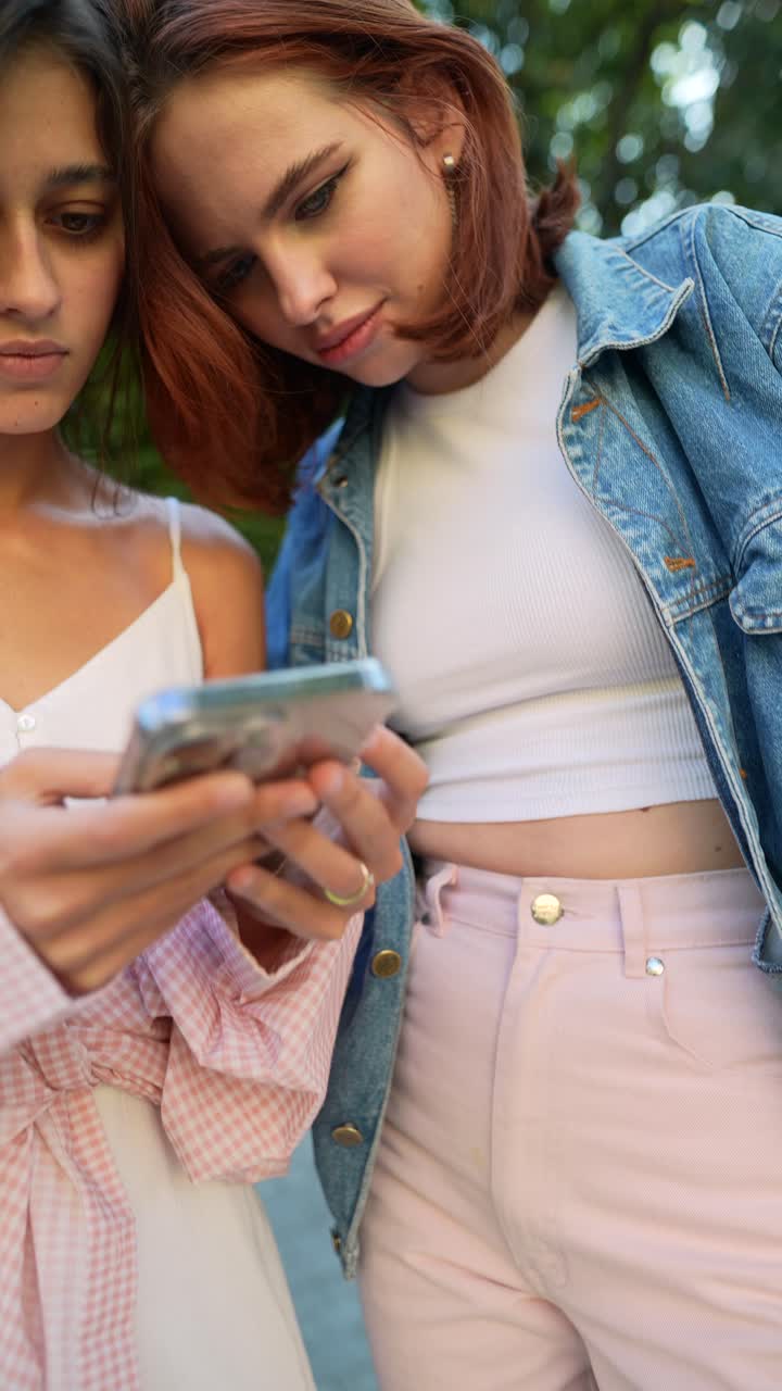 dos mujeres jóvenes mirando un teléfono inteligente