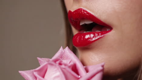 close-up of woman's red lips with pink rose
