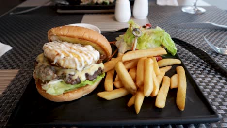 Ein-Köstlicher-Burger-Und-Pommes,-Serviert-Auf-Einem-Schönen-Schwarzen-Schieferteller