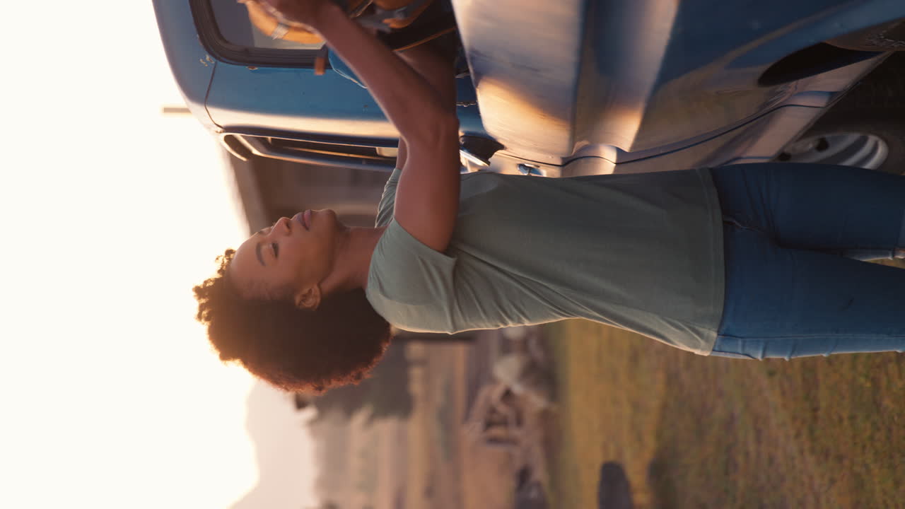 시골로 가는 도로 여행에서 픽업 트럭에서 배을 내리는 여성의 수직 비디오 초상화