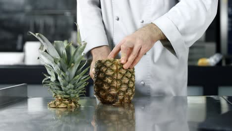 el chef cortando piña en cámara lenta. las manos del chef en primer plano cortando fruta fresca.