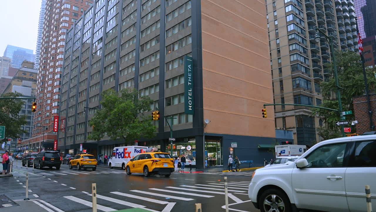 Street of New York on a usual rainy daytime. Cars and yellow cabs go by the road of metropolis
