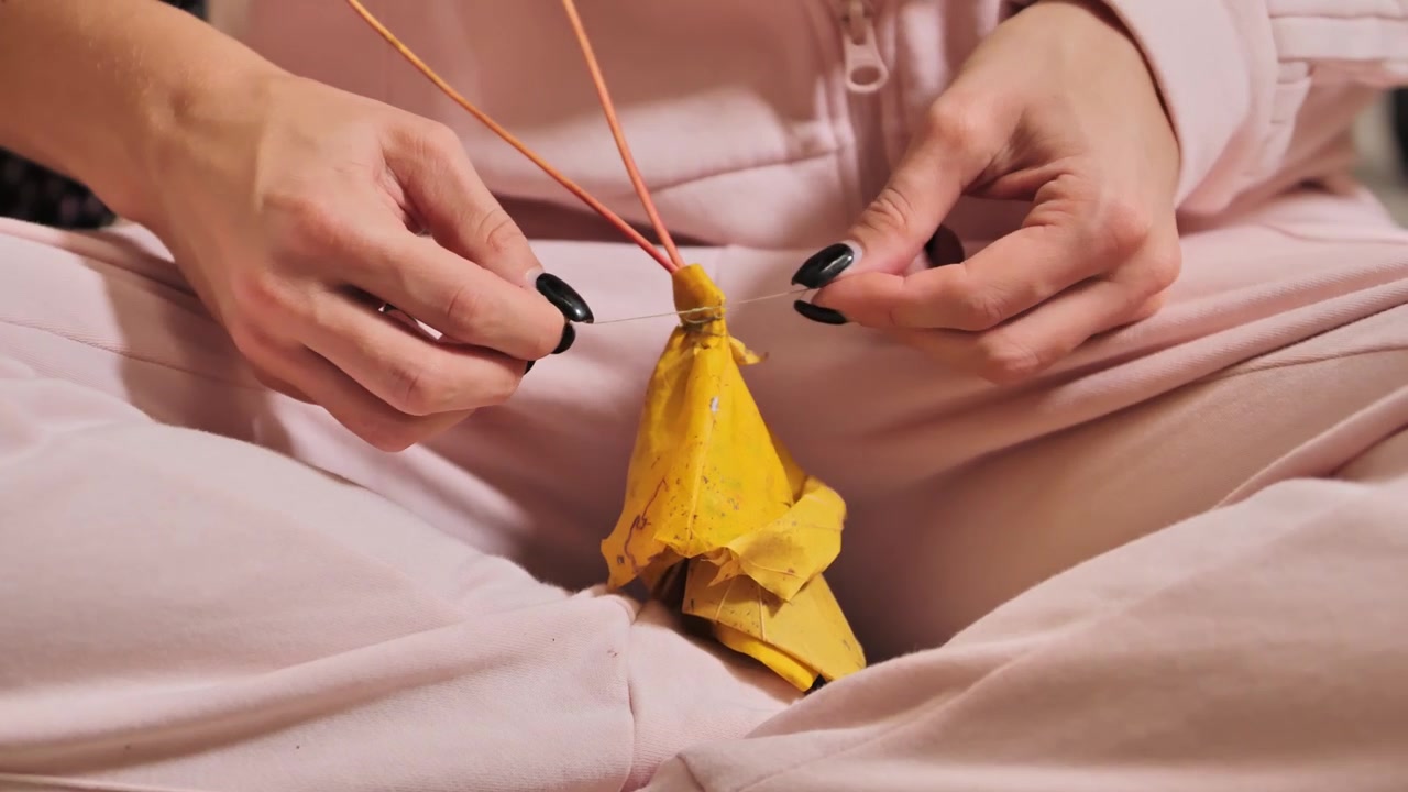 Primo piano di una donna che piega una foglia autunnale gialla a forma di rosa per decorazione.