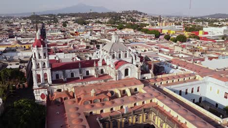 aerial bird's eye view panoramic forward shot over a historical church in puebla, mexico at daytime with the historical center mexican interesting spots for travel in america