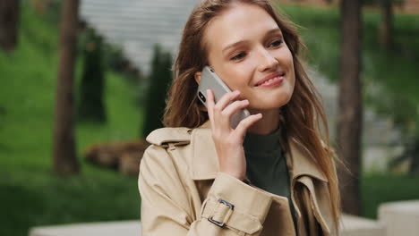 estudiante caucásica hablando por teléfono al aire libre.