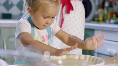 adorable little girl baking a tart with her mother