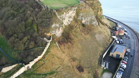 aerial parallax shot of a road near hill cliff beside a ocean during daytime in scarborough, england