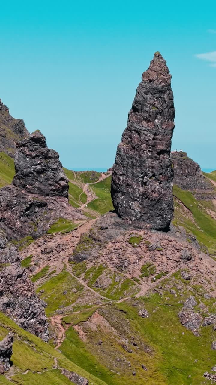 Maestose formazioni rocciose si ergono sopra le Highlands scozzesi sotto un cielo sereno.