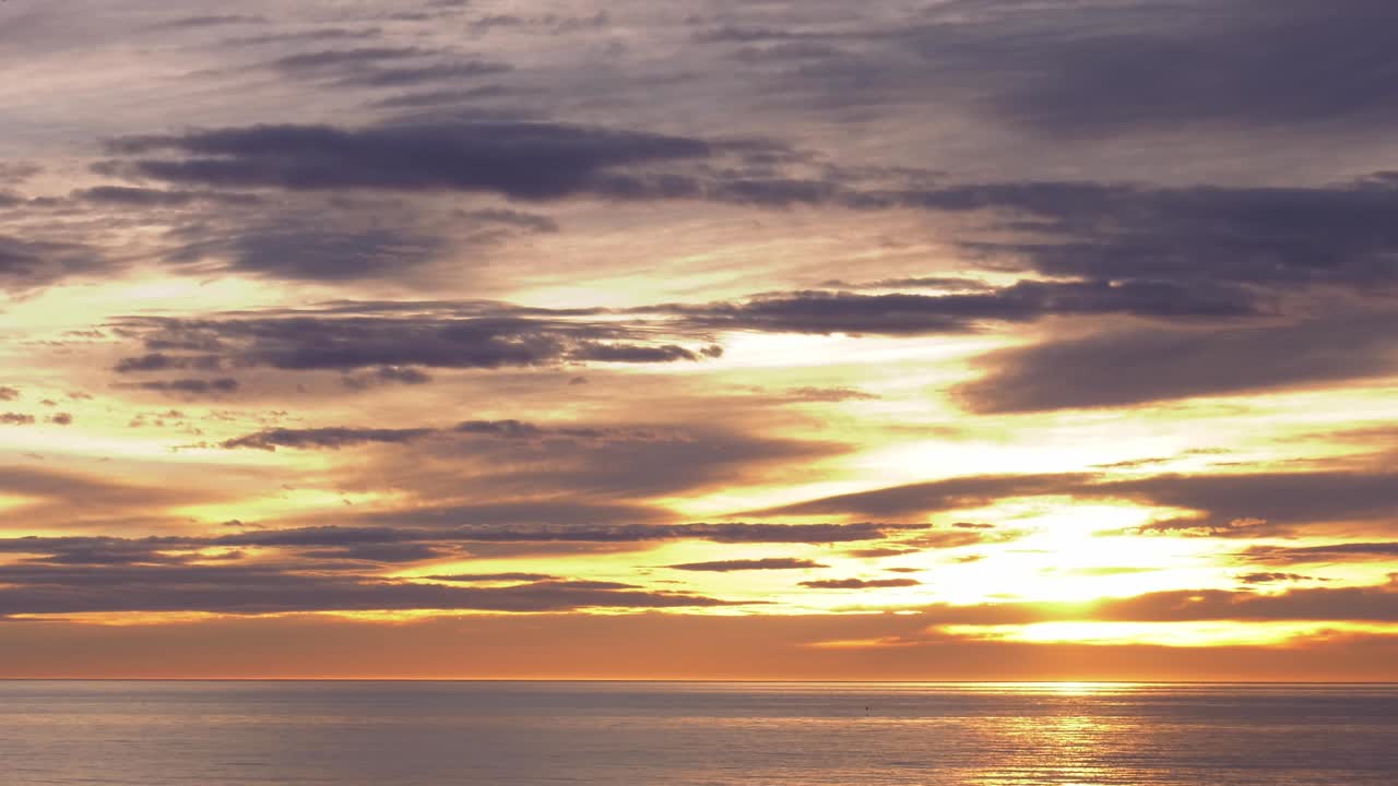Nature Timelapse of clouds moving over calm ocean at sunrise